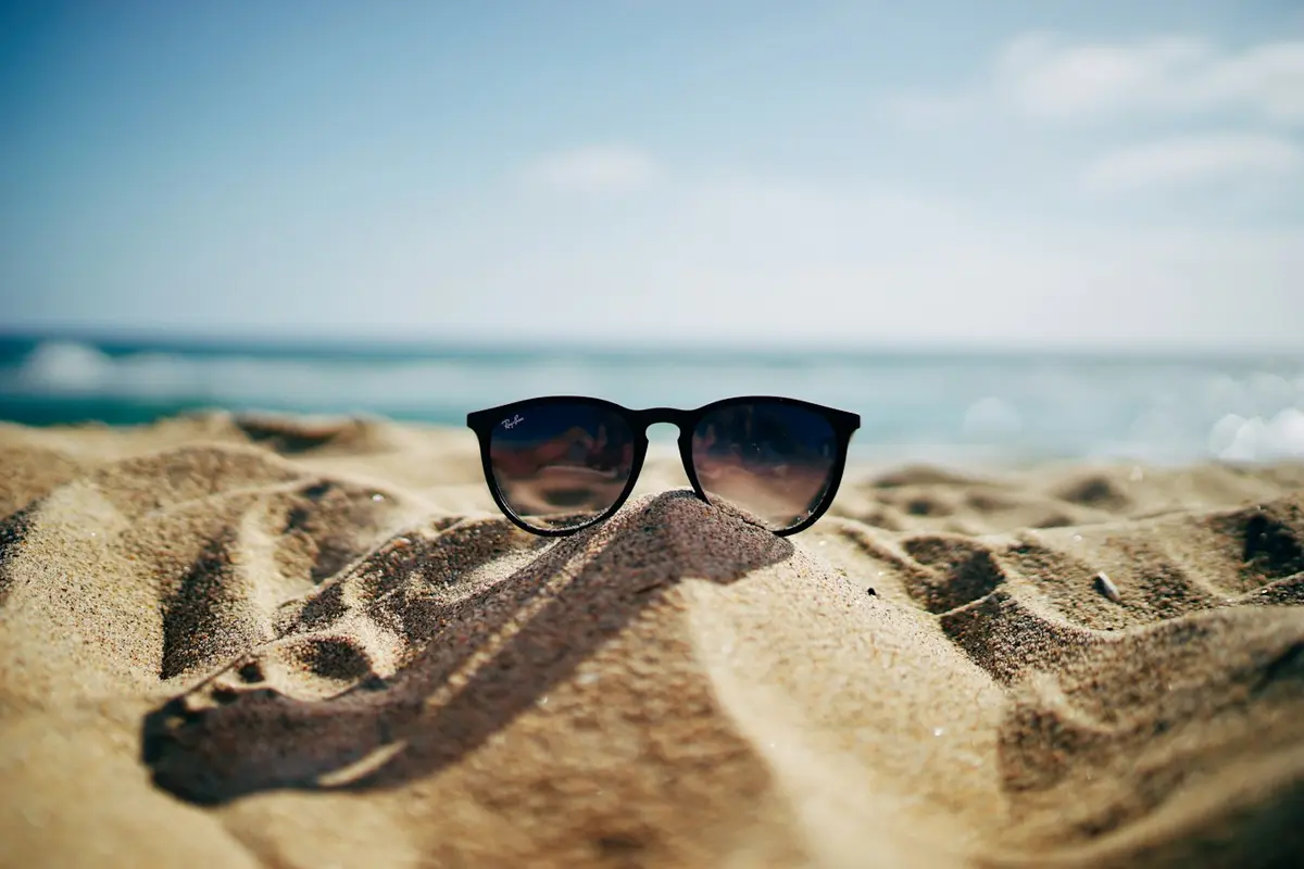 Sunglasses resting on warm beach sand